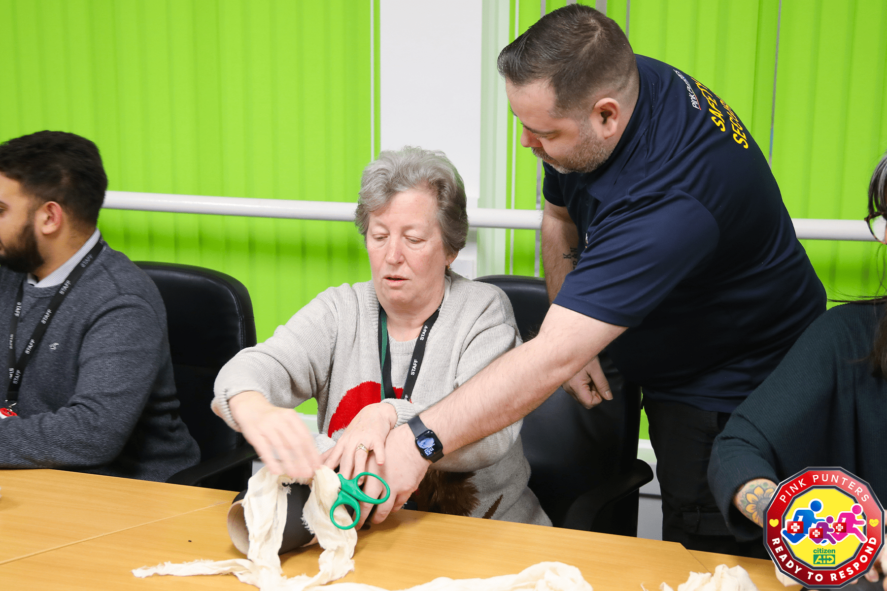 A staff member at Shenley Brook End School practicing a tourniquet with help from the Pink Punters team_